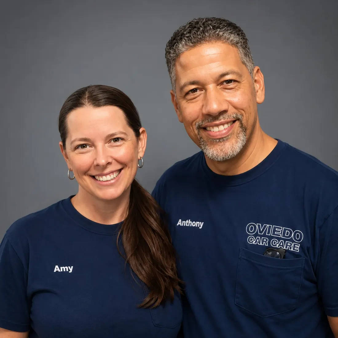 Amy and Anthony Pujols, owners of Oviedo Car Care, smiling in their navy shop shirts