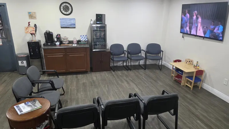 The Oviedo Car Care waiting area: comfortable chairs, a coffee station and beverage fridge, a wall-mounted TV, and a kids' play table in the corner